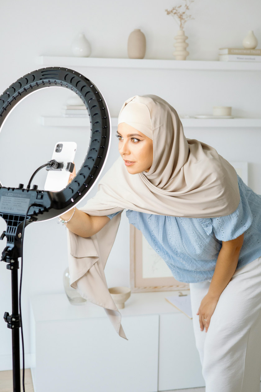 Woman setting up cellphone and light ring for filming